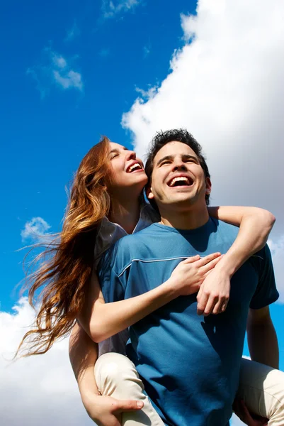Šťastný mladý pár proti obloze — Stock fotografie