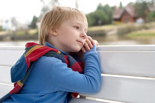 Den drömmande liten pojken på en bänk. — Stockfoto
