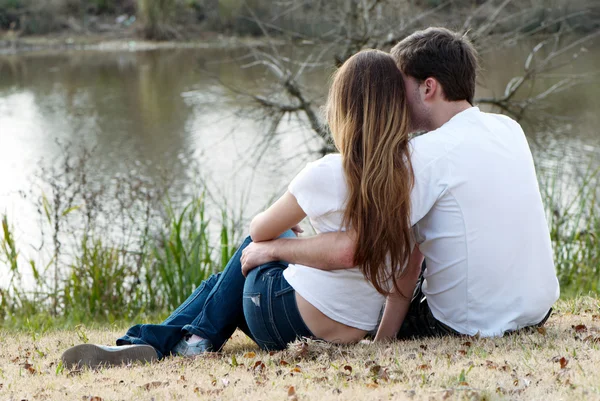 Giovane coppia seduta sulla riva del lago — Foto Stock