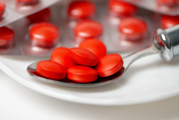 Rode tabletten in zilveren lepel — Stockfoto
