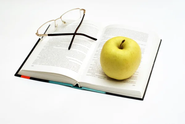 Pomme et lunettes sur le livre ouvert Images De Stock Libres De Droits