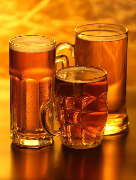 Beer mugs with froth over yellow — Stock Photo, Image