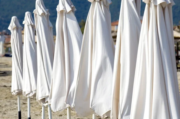Closed white parasols on beach — Stock Photo, Image