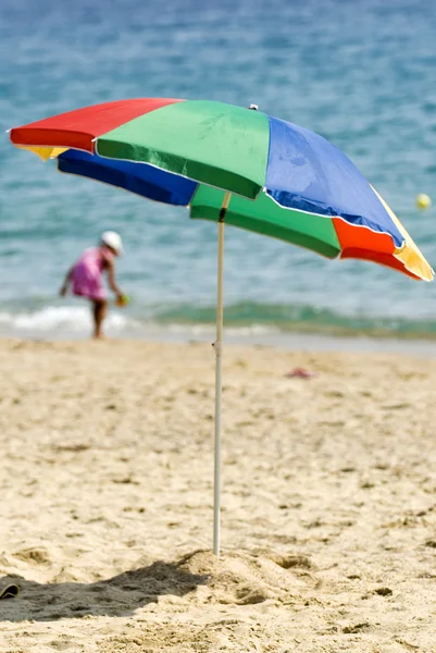 Полосатый зонтик на песчаном пляже — стоковое фото