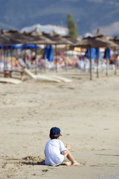 Yksinäinen lapsi leikkii rannalla — kuvapankkivalokuva