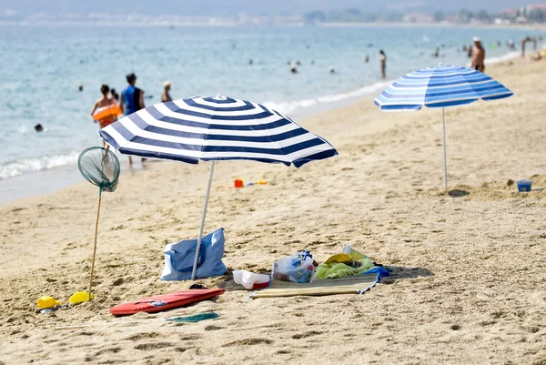 Meşgul sahilde iki güneş şemsiyeleri — Stok fotoğraf