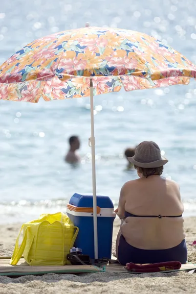Överviktig kvinna sitter på stranden — Stockfoto