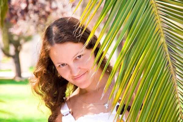 Chica alegre detrás de una rama de palma —  Fotos de Stock