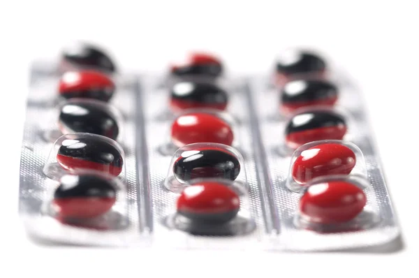 Rot-schwarze Pillen auf weißem Hintergrund Stockfoto