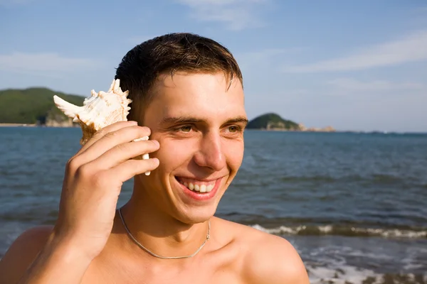 Genç adam ve deniz hayvanı kabuğu — Stok fotoğraf