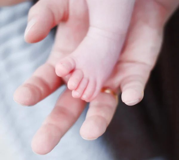 Babies foot and hand of man — Stock Photo, Image