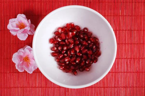 Red seeds and white bowl — Stock Photo, Image
