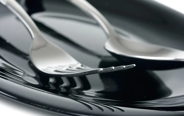 Tenedor y cuchara en plato negro — Foto de Stock