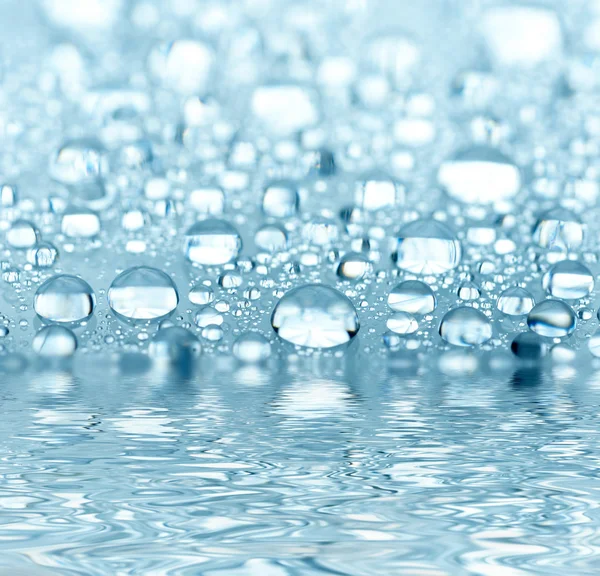 Blauwe druppels weerspiegeld in het water — Stockfoto