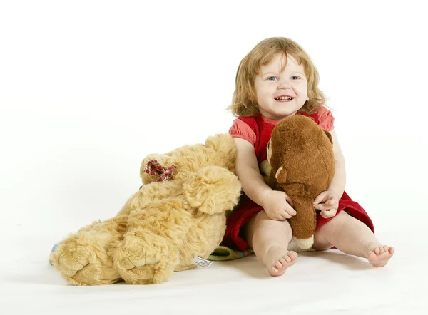 Den leende liten flickan med plysch leksaker. Stockbild