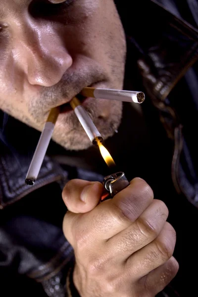 Young man smoking three cigarettes — Stock Photo, Image