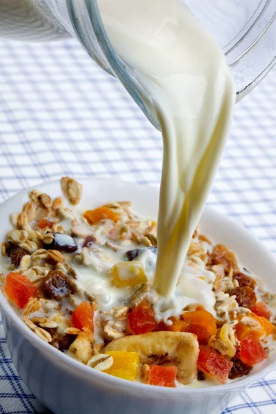 Pouring milk over muesli with dried frui — Stock Photo, Image