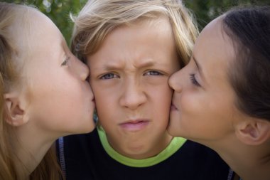 Young boy kissed by two girls clipart