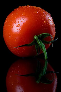 Raw tomato on black background clipart