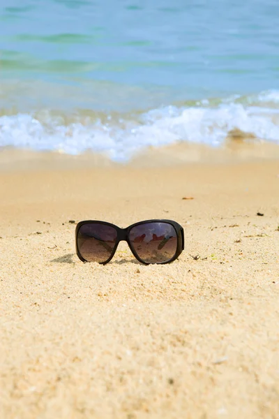 Güneş gözlükleri kumda duruyordu. — Stok fotoğraf
