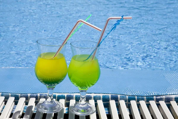 Glasses with cocktail on edge of pool — Stock Photo, Image