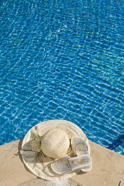 Slámový klobouk leží na pokraji bazénu — Stock fotografie