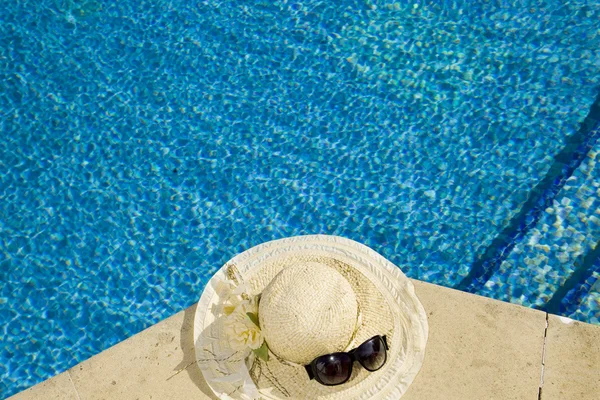 Słomkowy kapelusz leży na krawędzi basenu. — Zdjęcie stockowe