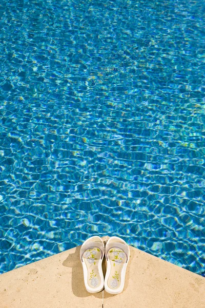 Тапочки лежат на краю бассейна — стоковое фото