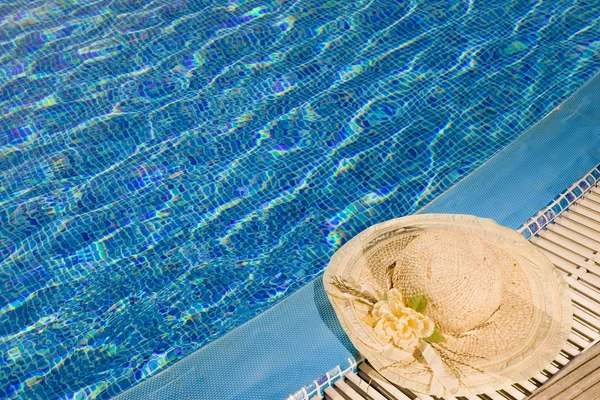 Соломенная шляпа лежит на краю бассейна — стоковое фото