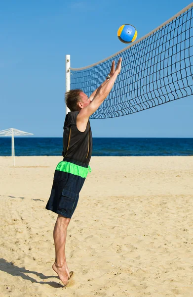 Спортивный человек играет в пляжный волейбол — стоковое фото