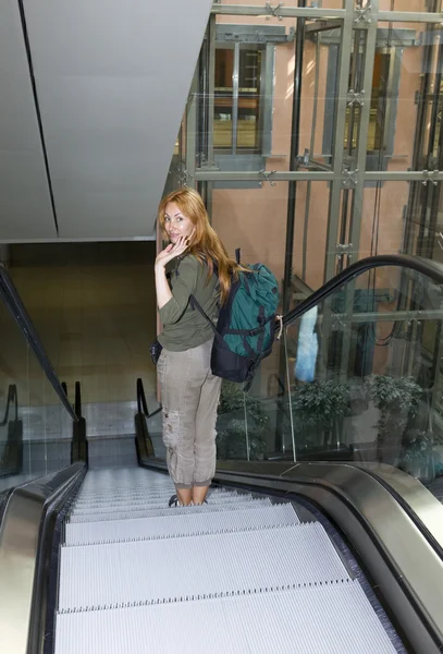 Frau mit Rucksack auf Rolltreppe — Stockfoto