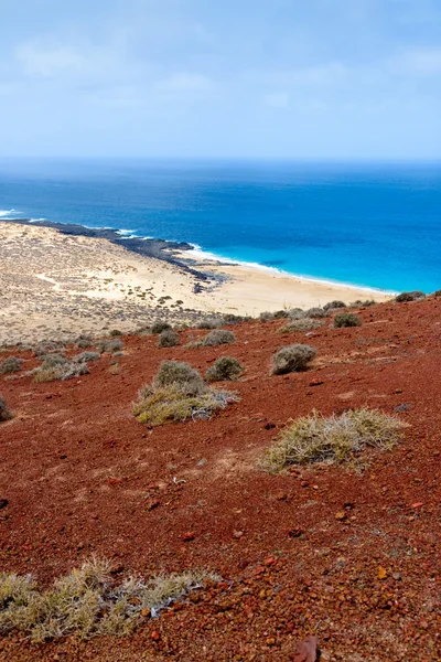 Playa de arena bajo un volcán rojo — Foto de Stock