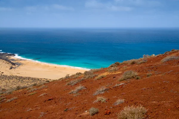 Playa de arena bajo un volcán rojo —  Fotos de Stock