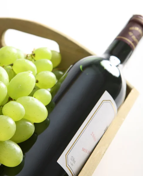 Botella de vino tinto junto a la uva blanca — Foto de Stock