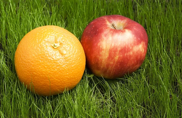 Яблоко и апельсин на траве — стоковое фото