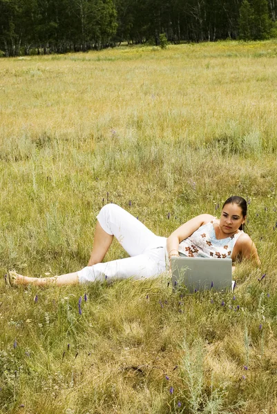 Mujer en el césped con el ordenador portátil — Foto de Stock