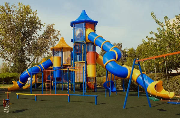 Um parque infantil público colorido em um jardim — Fotografia de Stock