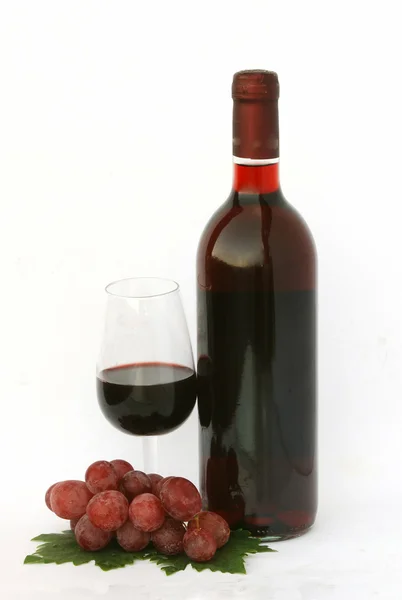 Botella de vino y copa con uvas Imagen de archivo