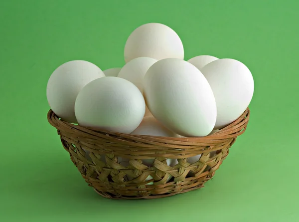 Ovos em cesta no fundo verde — Fotografia de Stock
