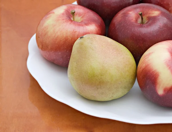 Pêra e maçãs em uma placa branca — Fotografia de Stock
