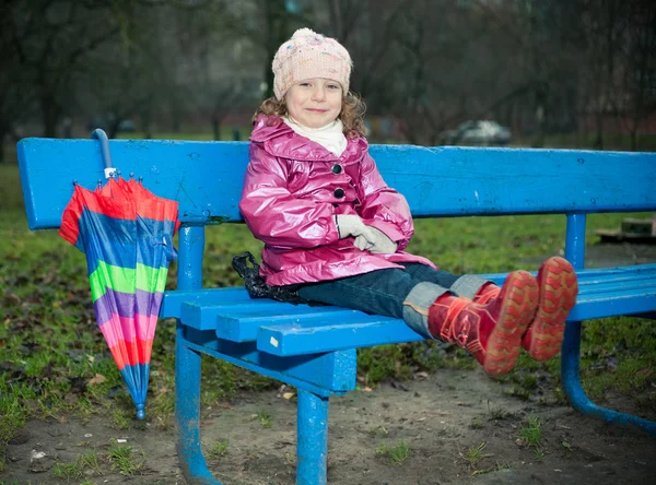 Menina senta-se no banco — Fotografia de Stock
