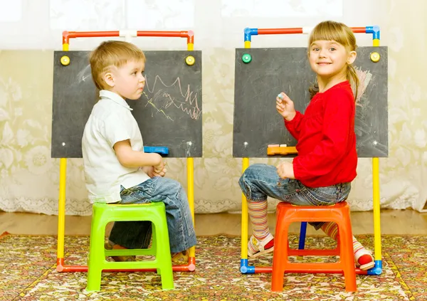 Дівчинка і хлопчик малюють на дошці — стокове фото