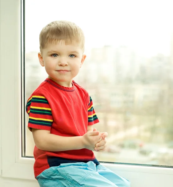 Chlapec sedí na okně — Stock fotografie