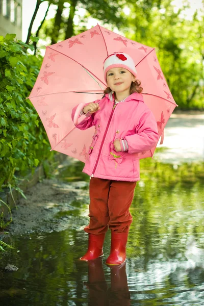 Girl in puddle with umbrella — Stock Photo, Image