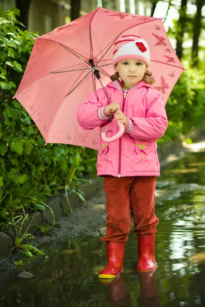 Girl in puddle with umbrella — Stock Photo, Image