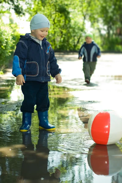 Boy with ball in the puddle — Stock Photo, Image
