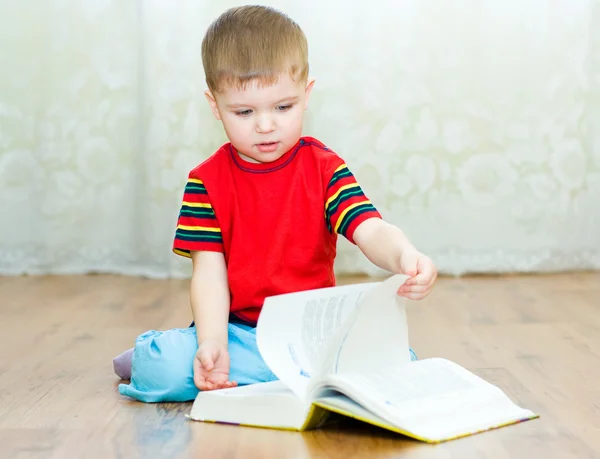 En liten pojke läser en bok — Stockfoto