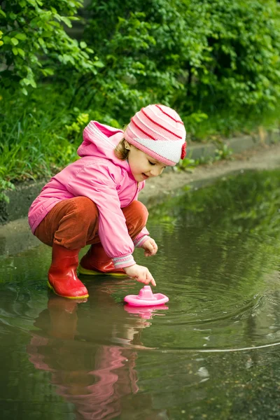 Маленькая девочка играет в луже — стоковое фото