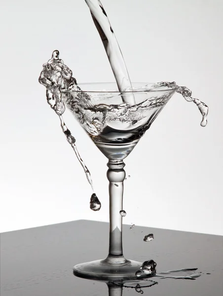 Νερό ρίχνει σε ένα ποτήρι μαρτίνι — Φωτογραφία Αρχείου