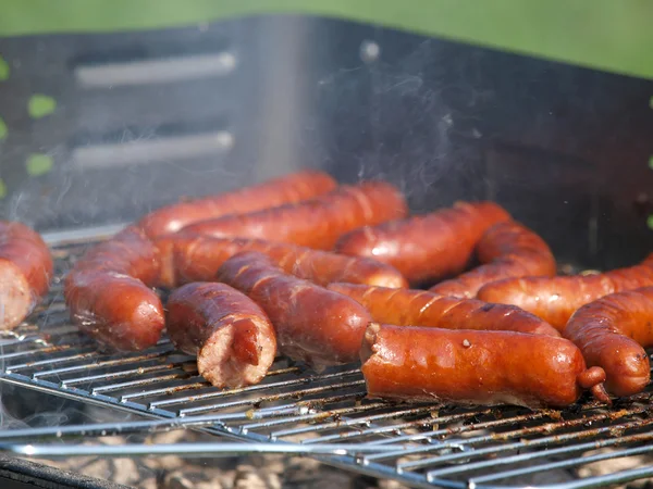 Many sausage on grill in garden — Stock Photo, Image